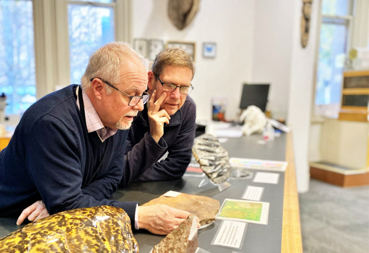 Two men with glasses peer at a rock sample in the Museum's Discovery Centre